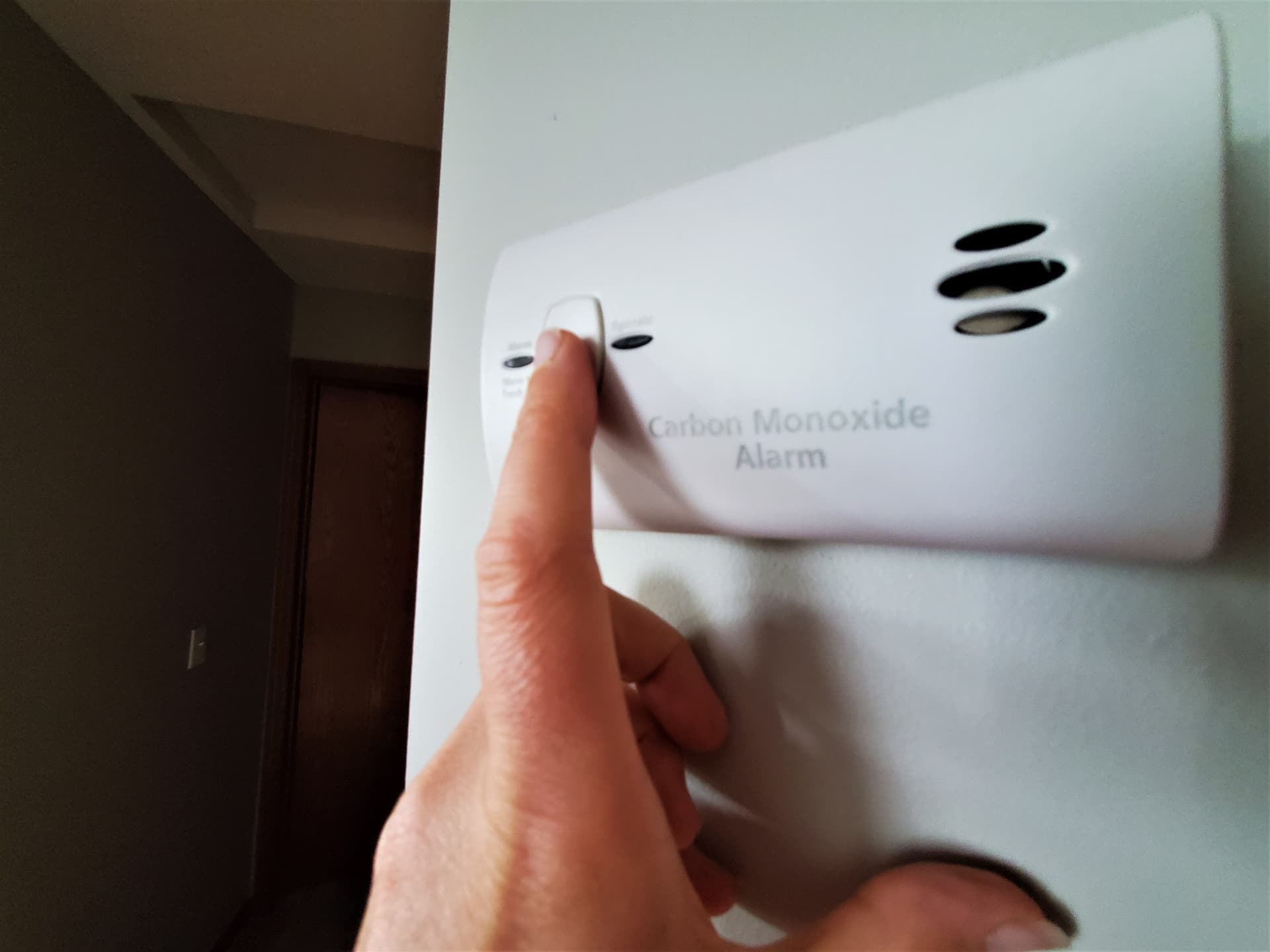 Someone presses the test button on a carbon monoxide alarm.