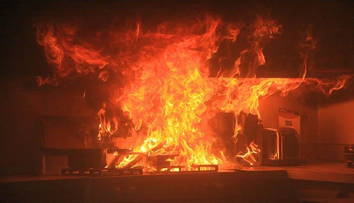 A fire explodes on a stove. 